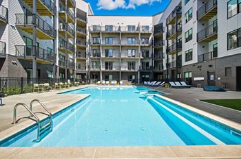 A large swimming pool in front of apartment buildings.